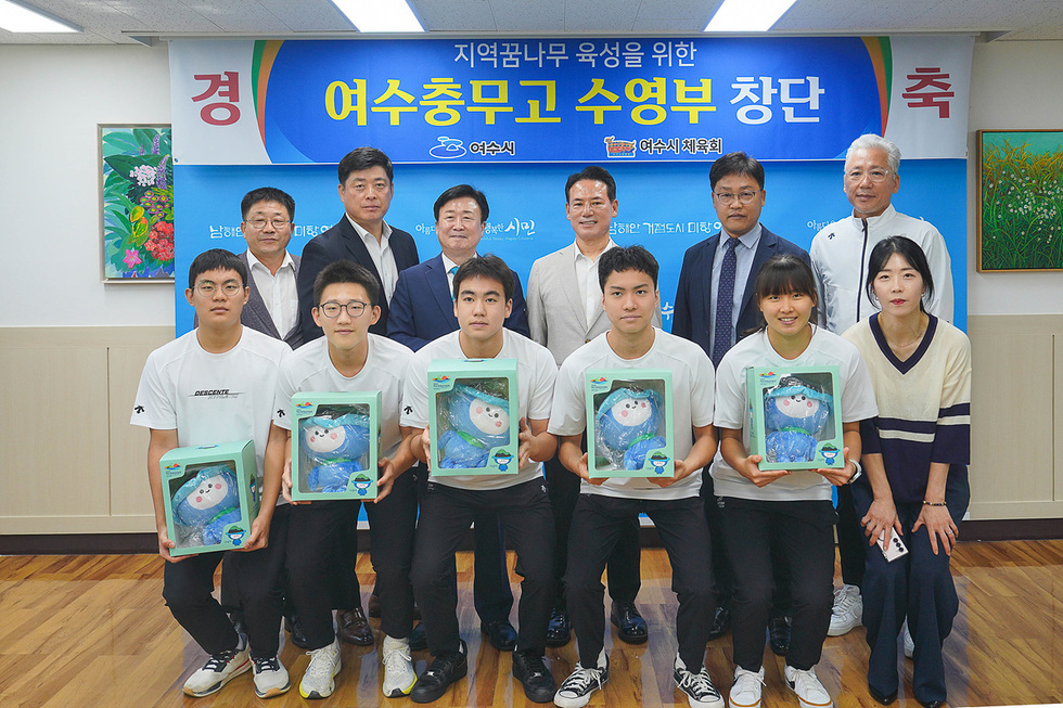 여수중무고 수영부 창단을 축하하는 행사에서 학생들과 관계자들이 기념사진을 찍고 있다. 학생들은 수영용품을 들고 있다.