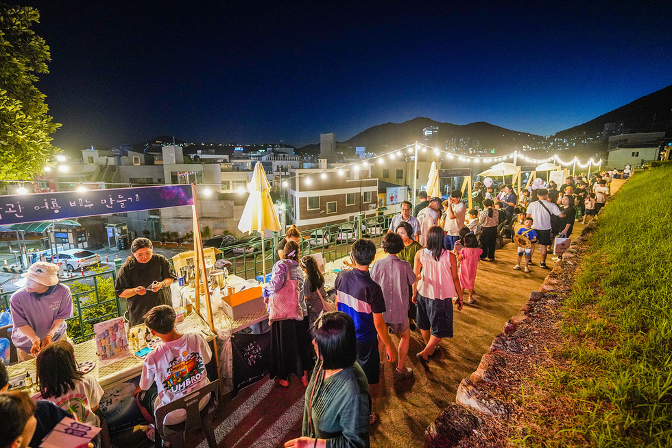 여수에서 열린 국가유산 활용 야간 축제 현장, 밤하늘 아래 노란 전등이 켜진 골목길에 체험 부스와 푸드존이 늘어서 있고 시민과 관광객들이 모여 활기차게 즐기는 모습