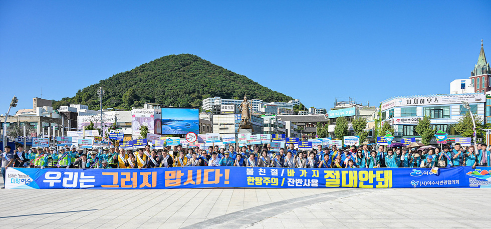 여수 이순신광장에서 친절관광 캠페인에 참여한 200여 명의 사람들이 우리는 그러지 맙시다! 불친절 바가지 한탕주의 잔반사용 절대안돼 현수막을 들고 있다.