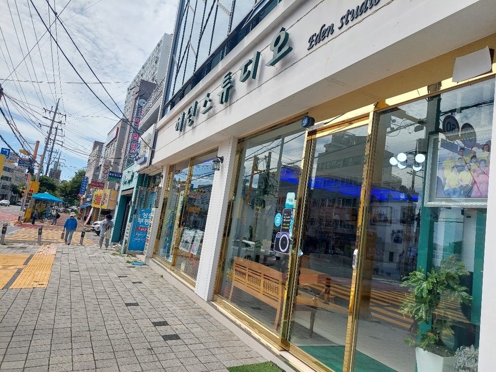 여수시에 위치한 에덴스튜디오 외관이 보이며, 주변에 보행자와 상점들이 있는 거리 풍경이다.