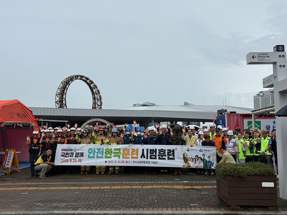 여수시에서 진행된 안전한국훈련에 참여한 200여 명의 관계자들이 국민과 함께 안전한국 훈련 시범훈련 현수막 앞에서 손을 흔들며 기념사진을 찍고 있다.