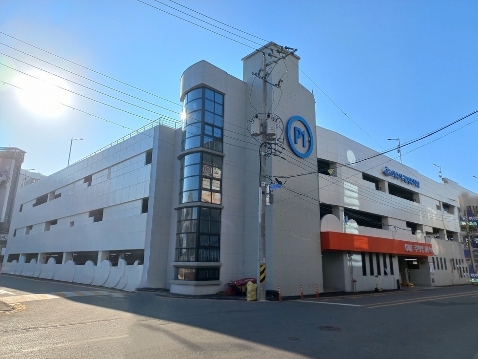 여수시의 유료 공영주차장 P1 외관이 보이며, 주차장 주변은 맑은 날씨로 청명한 하늘이 펼쳐져 있다.