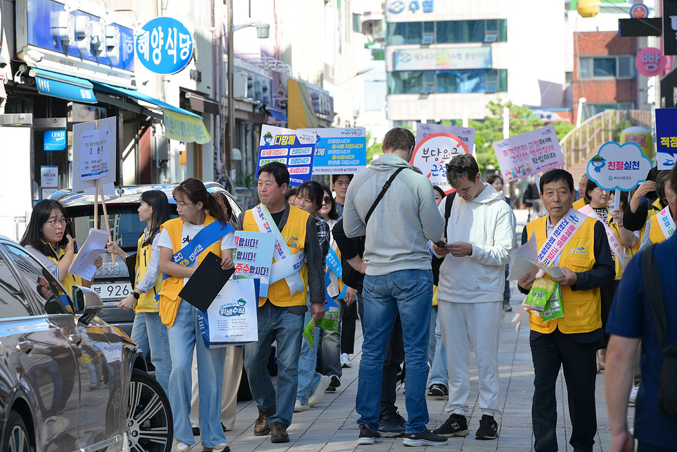여수에서 관광 안내를 위한 캠페인을 진행하는 자원봉사자들이 관광객들에게 정보를 제공하고 있다.