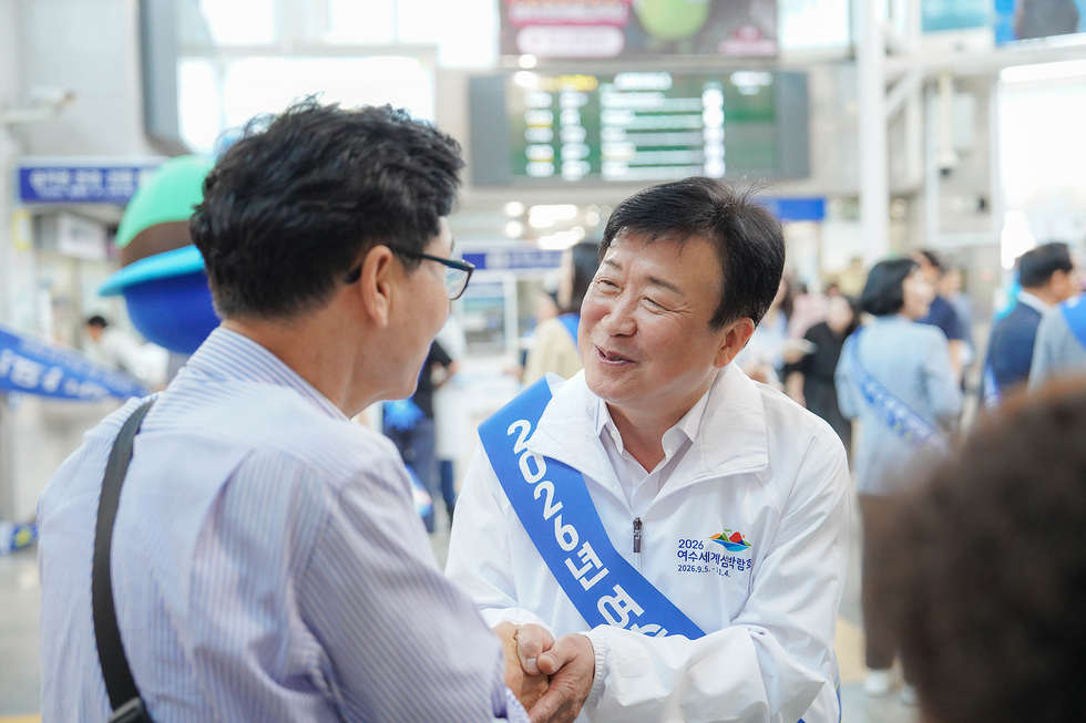 여수엑스포역 광장에서 정기명 여수시장과 시민이 인사를 나누며 2026여수세계섬박람회를 홍보하는 장면