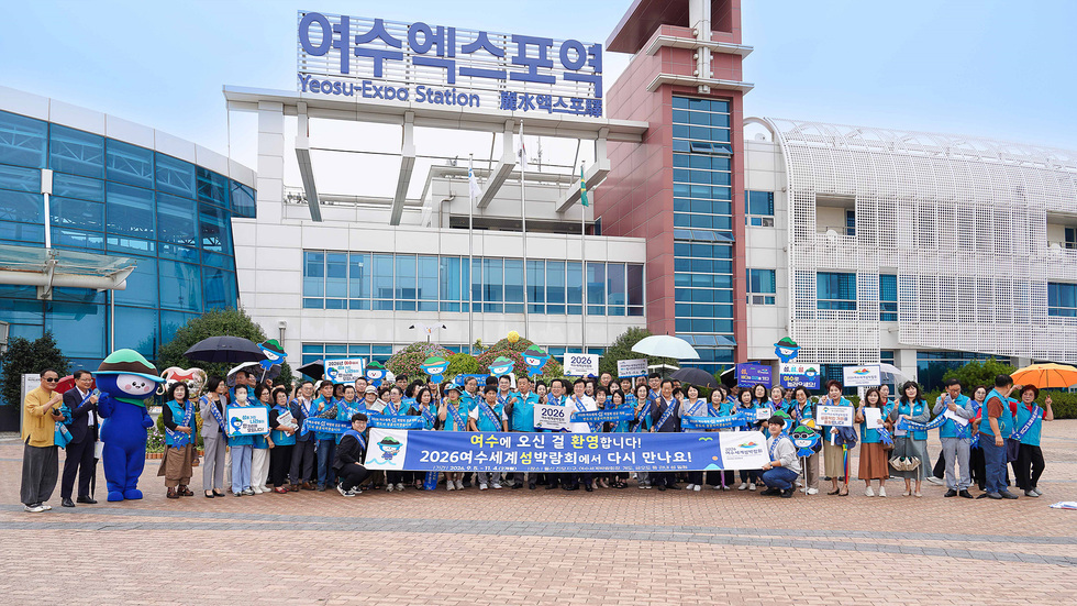 여수엑스포역 앞에서 2026여수세계섬박람회 홍보 캠페인에 참여한 100여 명의 시민들이 모여 기념사진을 찍고 있다