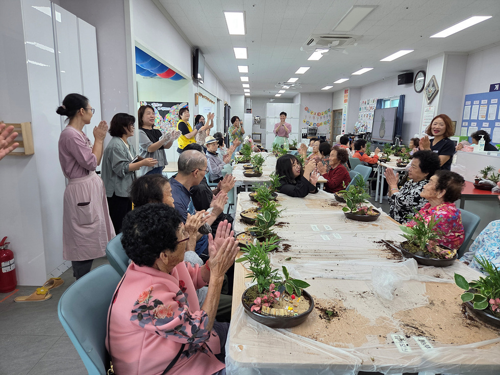 어르신들이 치유 원예교실에서 식물을 심으며 즐겁게 교류하고 있는 모습