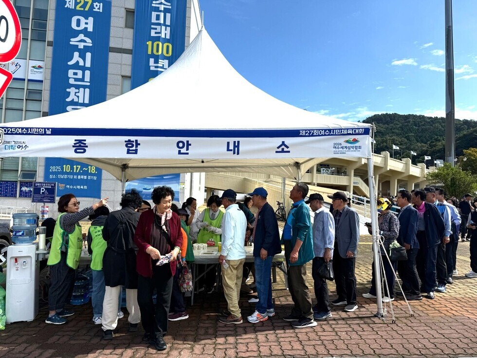 여수시민의 날 기념행사에서 시민들이 음료를 받기 위해 줄 서 있는 모습과 봉사자들이 음료를 제공하는 장면