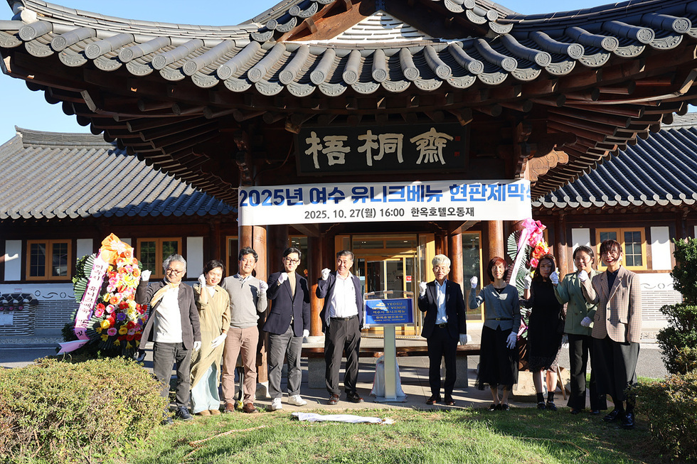 여수시 한옥호텔 오동재에서 2025 여수 유니크베뉴 현판식이 진행되고 있으며, 참석자들이 기념사진을 찍고 있다.