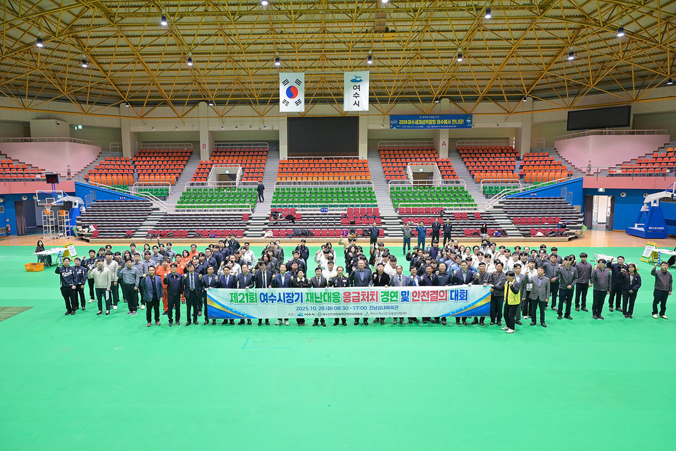 여수시 진남실내체육관에서 열린 제21회 여수시장기 재난대응 응급처치 경연 및 안전결의 대회에 참가한 200여 명의 인원이 현수막을 들고 기념사진을 촬영하고 있다.